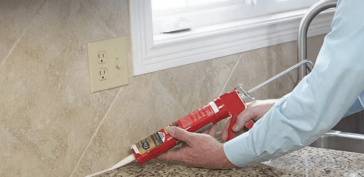 Handyman applying caulk along a kitchen backsplash and countertop seam in Columbia, SC