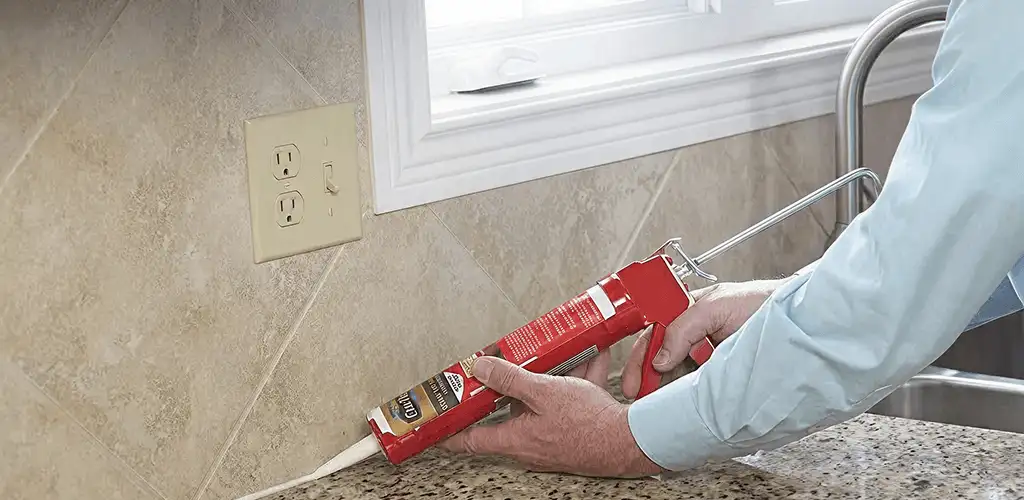 Handyman applying caulk along a kitchen backsplash and countertop seam in Columbia, SC