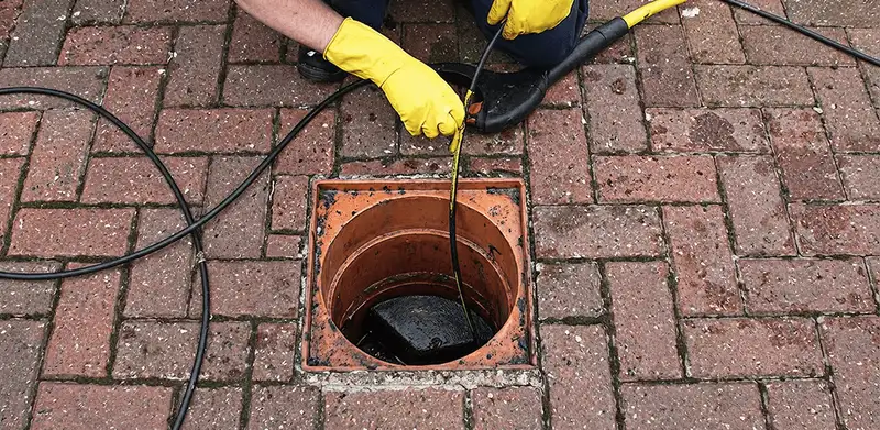 Drain cleaning technician using a drain snake to clear a clogged drain in Columbia, SC