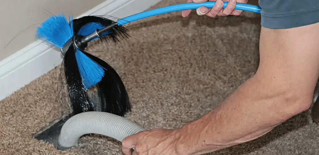 Dryer vent cleaning technician brushing lint from a vent line in Columbia, SC
