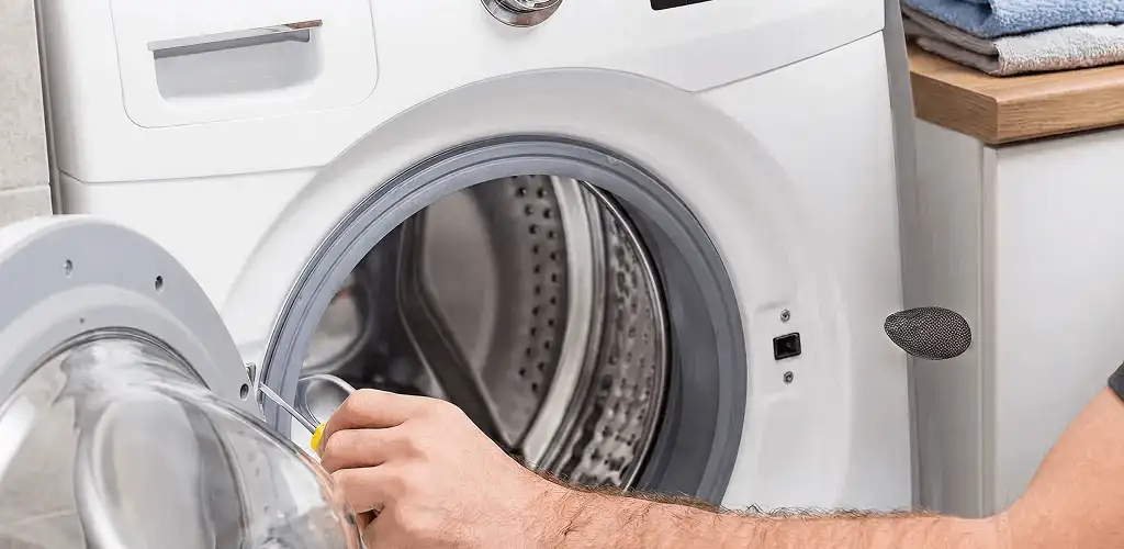 Handyman repairing a front-load washing machine and inspecting the drum in Columbia, SC