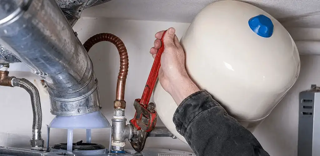 Water heater repair technician tightening plumbing connections near a tank unit in Columbia, SC