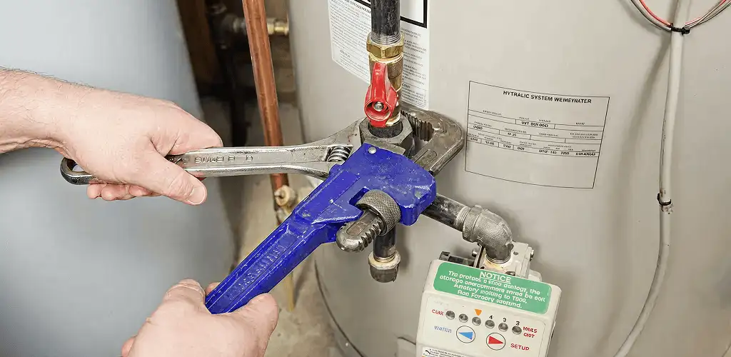 Water heater repair technician tightening the shutoff valve and supply line in Columbia, SC